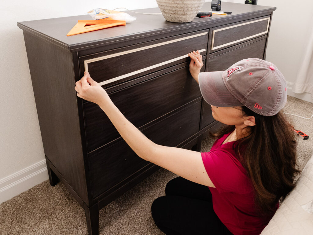 IKEA dresser and girl attaching trim for a DIY